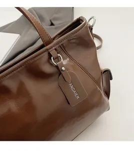Detail of dark brown leather tote bag showing glossy texture and large capacity