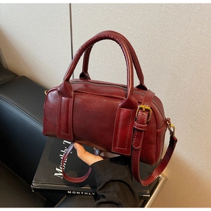 Detailed view of the dark red leather Boston bag with brass hardware and handles