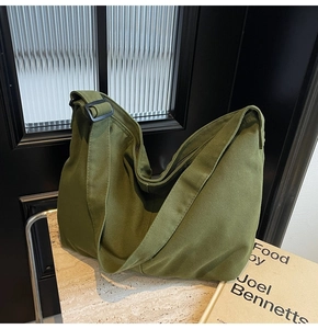 Nahaufnahme der armygrünen Canvas-Tasche mit verstellbarem Gurt auf Marmoroberfläche
