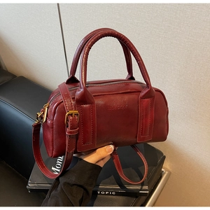 Detail of burgundy leather Boston bag with embossed logo and bronze hardware accents