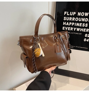 Detailed close-up of dark brown PU leather tote bag with baseball themed charm and handle