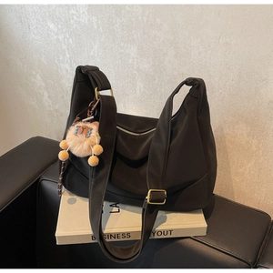 Detail of black nylon crescent bag featuring wide shoulder strap and cute lion charm