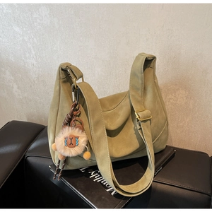 Close-up of green suede hobo bag with gold hardware and a cute sheep charm detail