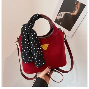 Détail du sac seau rouge en similicuir avec foulard à pois et logo triangulaire doré