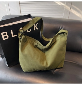 Detail einer olivgrünen Canvas-Tasche mit verstellbarem Gurt auf Ledersofa