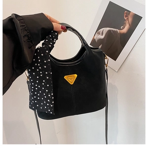 Détail du sac à main noir givré avec logo métallique et poignée en écharpe à pois