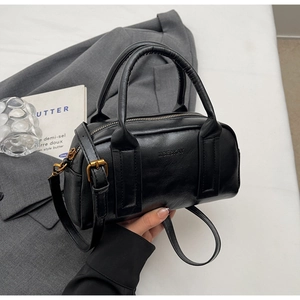 Detail of black pebbled leather Boston bag with vintage gold hardware and dual handles