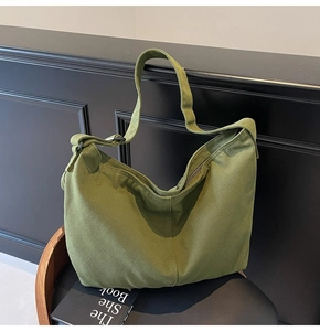 Nahaufnahme der olivgrünen Canvas-Tasche mit verstellbarem Riemen auf minimalistischem Stuhl