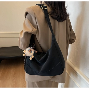Detail of black crescent crossbody bag with adjustable wide strap and lion plush charm