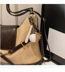 Detail of baseball keychain with wooden bat and leather glove on a tote bag