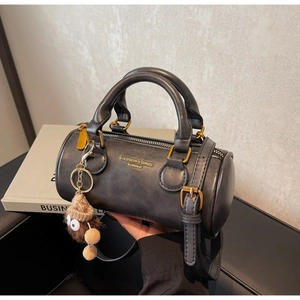 Detail of black cylindrical Boston bag with gold lettering and cute plush charm