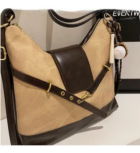 Detail of color-block tote bag featuring metallic gold buckles and a baseball charm pendant
