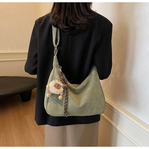Detail of green dumpling crossbody bag with lion plush pendant and woven tassel on strap