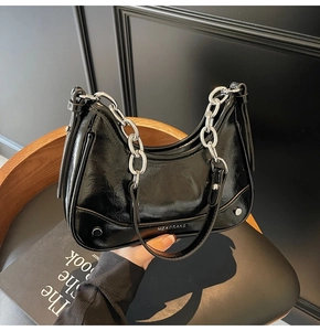 Détail du sac demi-lune en cuir verni noir avec texture plissée et chaîne en métal argenté