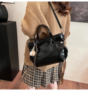 Close-up of shiny black patent leather tote bag featuring side pocket and athletic charms