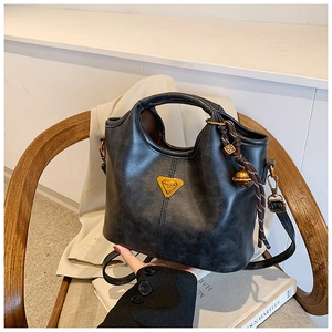 Détails du cabas vintage en cuir noir avec logo triangulaire et breloque cloche tressée