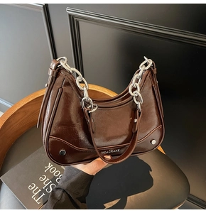 Détail du sac hobo en cuir verni marron foncé avec chaîne argentée et rivets métalliques