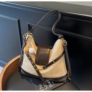 Detail of beige canvas tote with brown leather accents and baseball themed charms