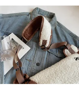 Detail of white plush crossbody dumpling bag with brown adjustable strap and shoulder pad