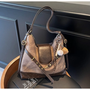 Detail of vintage canvas tote with leather trim and baseball charm on a chair