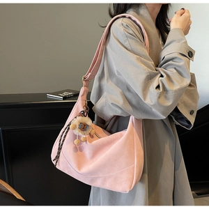 Detail of pink hobo bag in faux suede featuring cute plush lion charm and wide strap