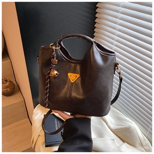 Détail du sac cabas en cuir marron foncé avec logo triangle en métal et pendentif