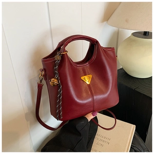 Détail du sac seau en cuir bordeaux avec logo en métal et bandoulière