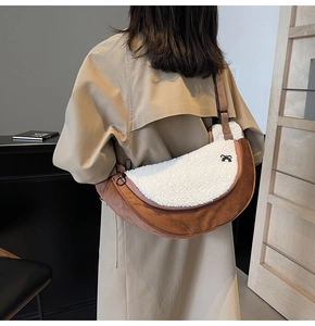 Detail of white plush and brown suede crescent bag with a small black bow accent