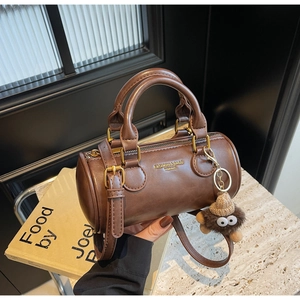 Close-up of brown cylinder bag featuring leather texture and golden brand lettering