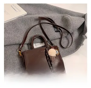 Détail d'un sac à main en cuir marron foncé avec charm en peluche et bandoulière