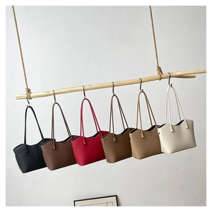 Sacs cabas minimalistes en six couleurs avec texture cuir grainé suspendus à une tige en bois