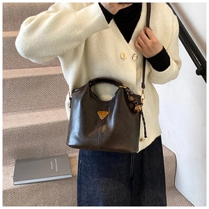 Détail du sac cabas en cuir marron vintage avec logo doré et pendentif tressé