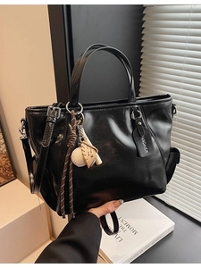 Large black glossy leather tote bag with baseball pendant and adjustable shoulder strap