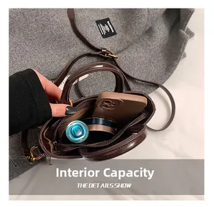 Vue intérieure du mini sac en cuir verni marron montrant la poche zippée et le rangement