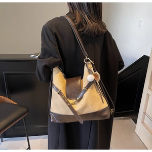 Back view of model carrying khaki canvas and brown leather tote with a baseball charm