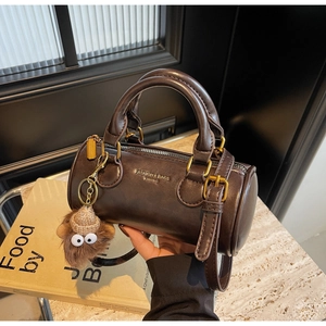 Close-up of vintage brown barrel bag with plush monkey charm and golden logo detail