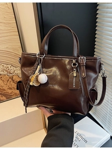 Large dark brown oil leather tote bag with baseball pendant and adjustable shoulder strap