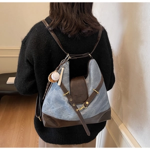 Detail of blue denim and brown leather tote showing the versatile shoulder straps