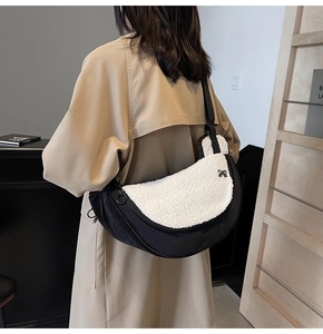 Detail of plush crescent crossbody bag with black bow and adjustable strap on model