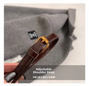 Détail de la bandoulière réglable en cuir marron foncé avec une boucle en métal doré