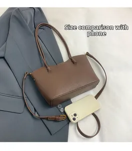 Sac fourre-tout en cuir marron grainé à côté d'un smartphone pour comparer la taille