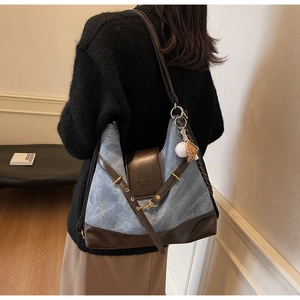 Detail view of denim and brown leather tote with a creative baseball glove charm