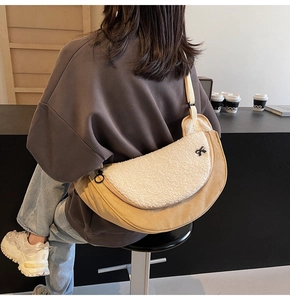 Detail of beige faux fur crescent bag with a black bow and wide crossbody strap