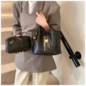 Détail du sac fourre-tout en cuir noir avec logo triangulaire doré et pochette assortie