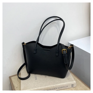 Détail du sac cabas en cuir noir avec texture grainée et boucles métalliques dorées