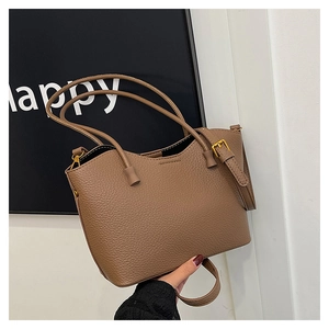 Détail du sac cabas en cuir marron avec texture litchi et finitions métalliques dorées
