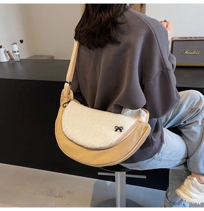 Detail of plush crescent crossbody bag with white faux shearling and black bow charm