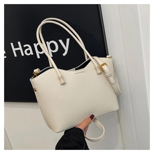 Détails de la texture du cuir et des boucles dorées sur le sac fourre-tout beige chic