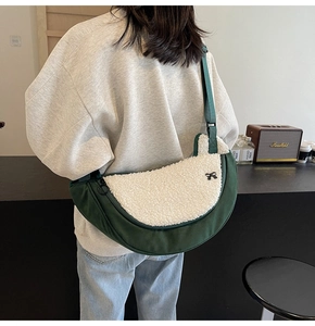 Detail view of dark green plush crescent bag with a decorative black bow accent