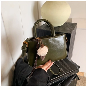 Borsa a mano in pelle verniciata verde scuro con ciondolo in peluche in stile minimal